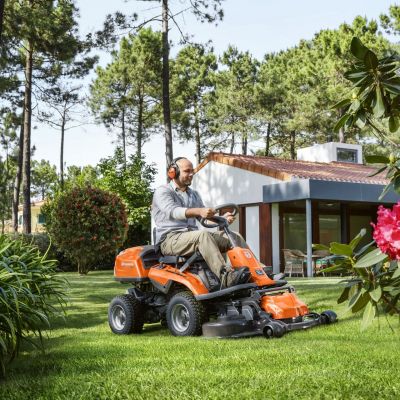 Mann fährt Rasentraktor im Garten